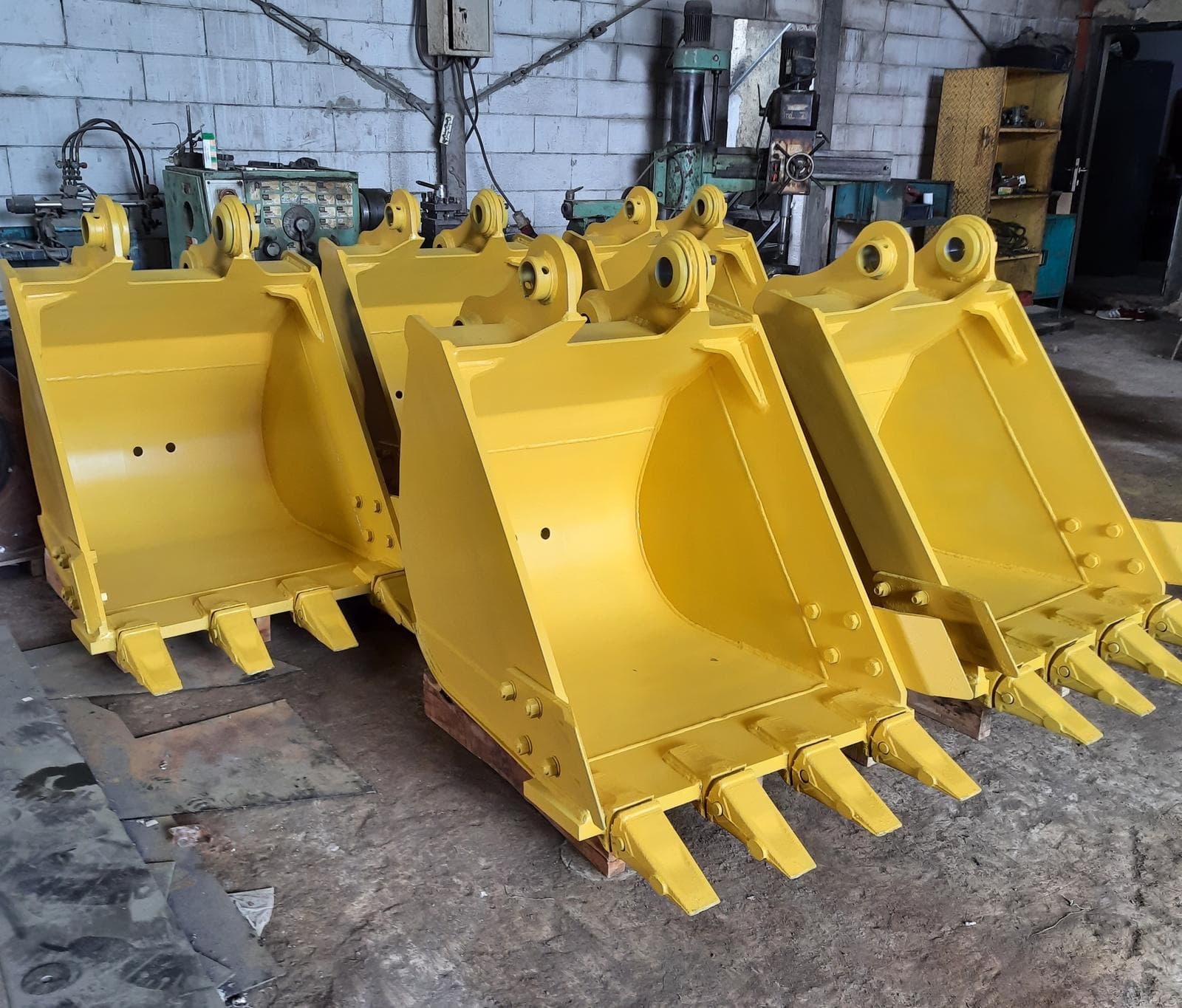 A row of finished yellow excavator buckets on the shop floor
